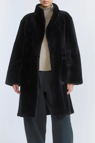 front profile model wearing untied Manteau Reversible Jacket Storm black fur side Midi length coat
Two faces of a Merino lambskin shearling
Reversible, it can be worn with the skin side or the wool side facing out
High collar
Matching belt
Welt pockets
Unlined
100% Lamb