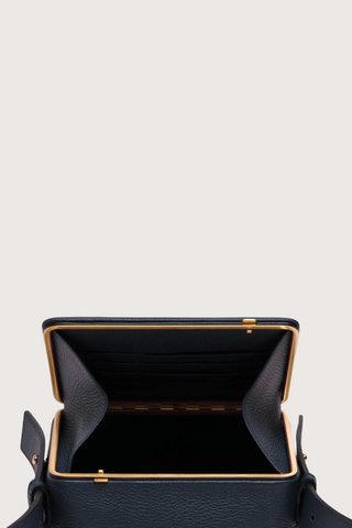 opened view of Maya Brandon Navy Bag pebbled leather exterior back pocket adjustable strap structured square shape with Stainless steel frame is 24k gold-plated and seven interior card slots