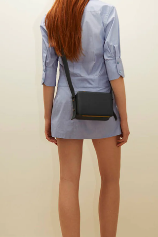 model wearing Maya Brandon Navy Bag pebbled leather exterior back pocket adjustable strap structured square shape
