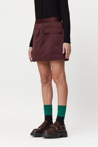 side profile model wearing Mini Skirt With Pockets, Burgundy mini skirt, Duchesse satin, Hip flap pockets, Concealed back zipper closure