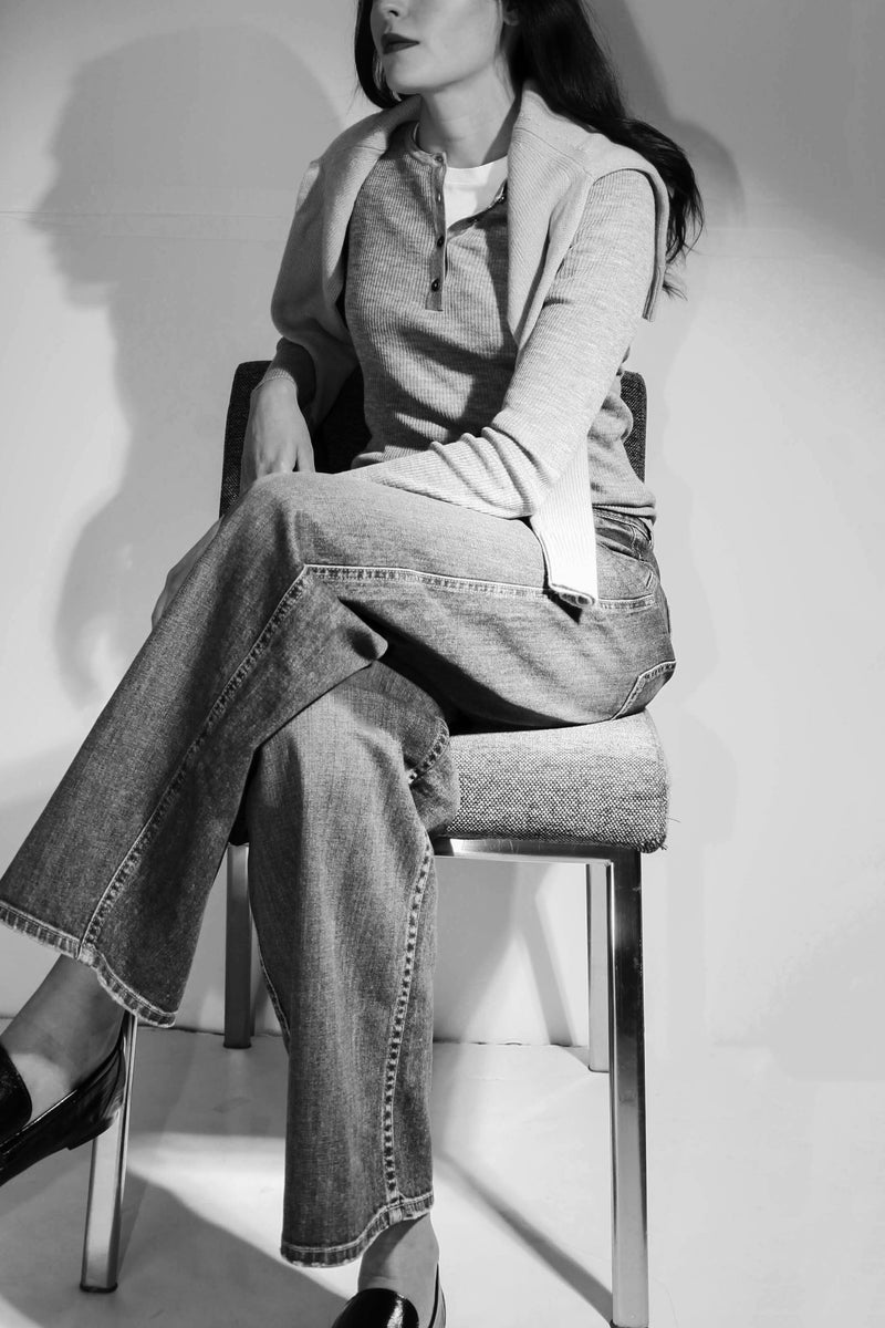 black and white image of Model sitting down wearing nili lotan henley, swaeter over her shoulder and jeans. 