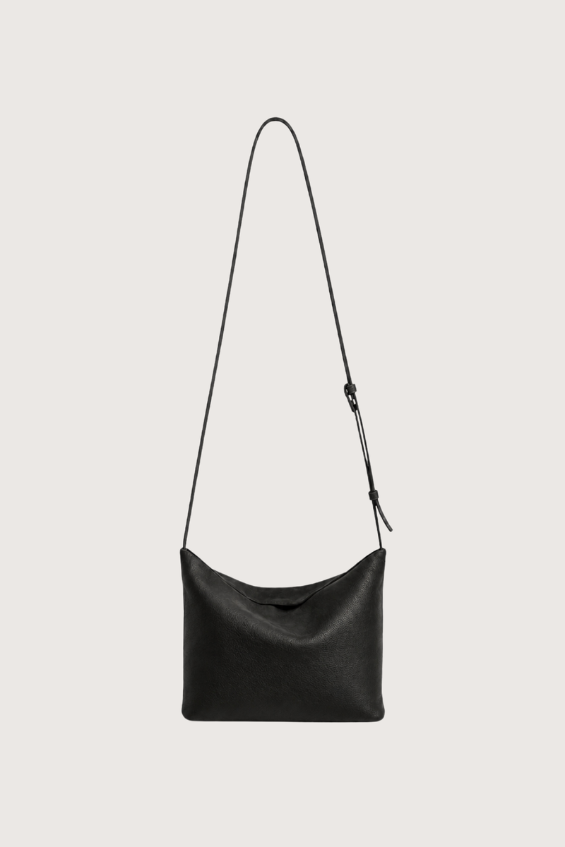 flat lay with strap expanded Moore Cross Body Bag Ink black Folded leather panel construction
Top zip closure
Two separate interior compartments
Adjustable strap is fixed on the interior
100% Calfskin Leather
