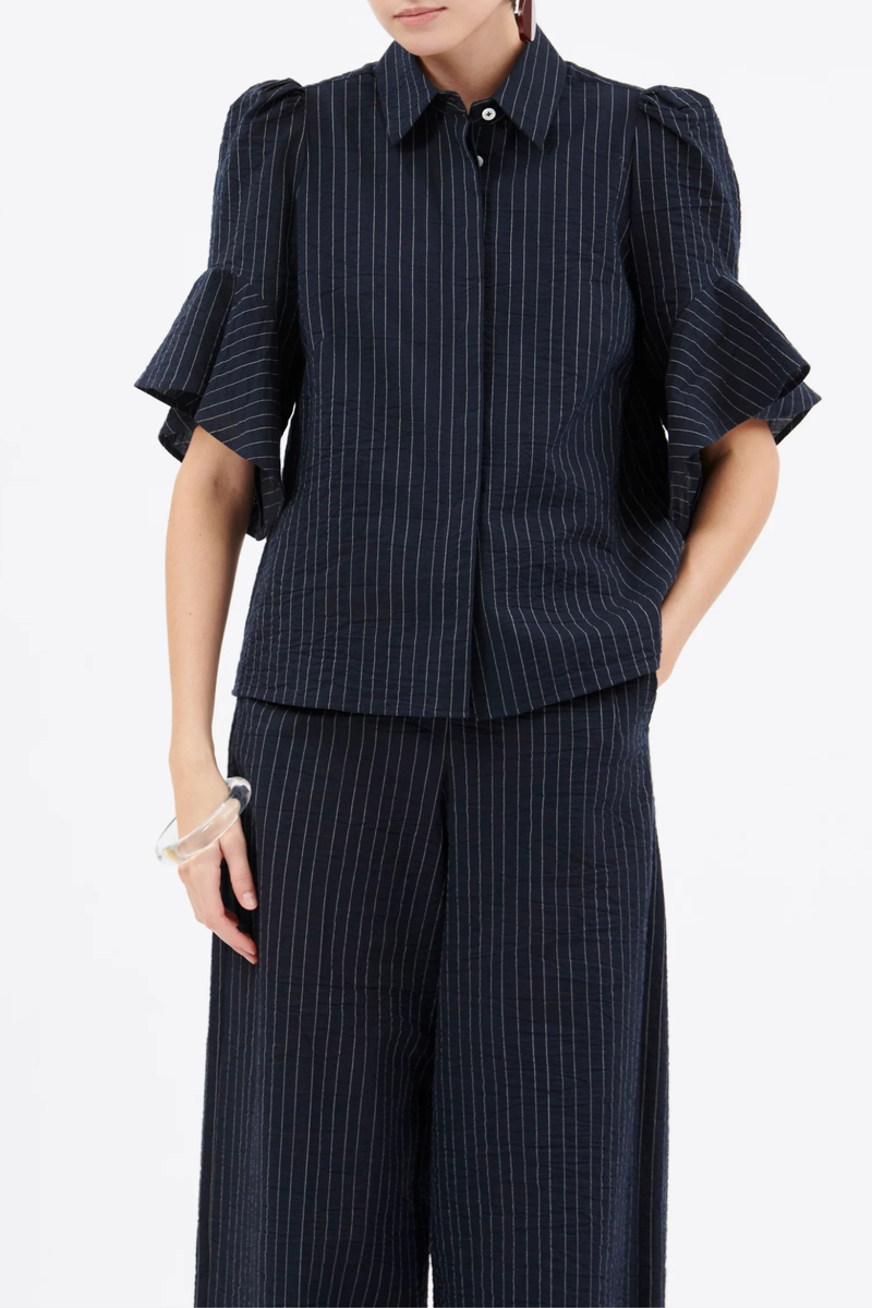 front profile model wearing Organza Stripe Short Sleeve Top ink blue cotton Vertical stripe
Concealed button placket
Classic collar
Short sleeves
Ruffle at the hem