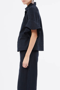 side profile model wearing Organza Stripe Short Sleeve Top ink blue cotton Vertical stripe
Concealed button placket
Classic collar
Short sleeves
Ruffle at the hem