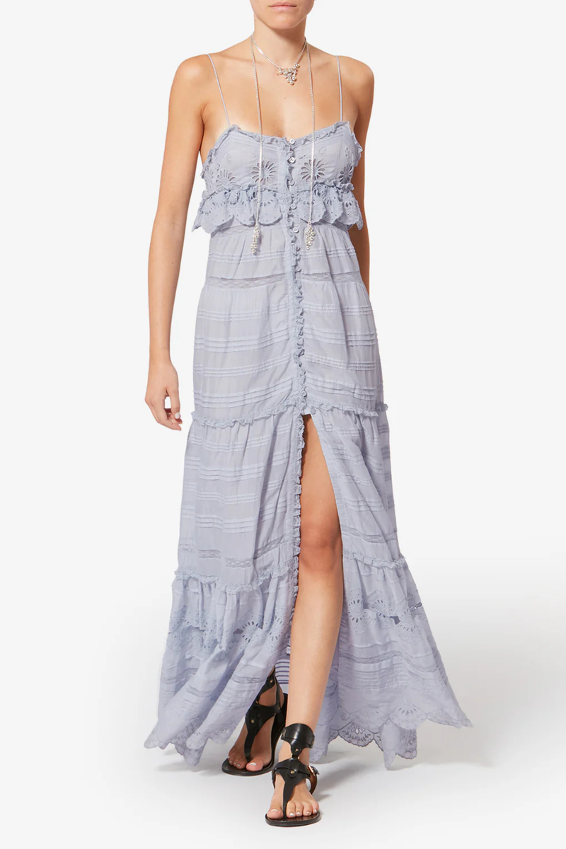 front profile model wearing  Paule Cami Maxi Dress Light Blue Long organic cotton and floral lace dress
Low-cut V-neckline
Thin adjustable straps
Buttoned front
Frills with a crochet finish and pintucks
Lined
Flared cut
100% cotton