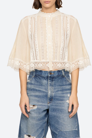 front profile model wearing Pippa Solid Short Sleeve Top Short sleeve
Softly raised neckline
Delicate pleating
Lace inserts throughout
Cropped silhouette
Floral lace hem
Airy, flowing sleeves
100% cotton
Button front