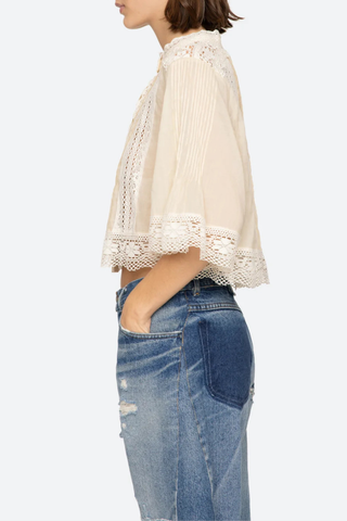 side profile model wearing Pippa Solid Short Sleeve Top Short sleeve
Softly raised neckline
Delicate pleating
Lace inserts throughout
Cropped silhouette
Floral lace hem
Airy, flowing sleeves
100% cotton
Button front