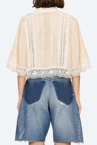 back profile model wearing Pippa Solid Short Sleeve Top Short sleeve
Softly raised neckline
Delicate pleating
Lace inserts throughout
Cropped silhouette
Floral lace hem
Airy, flowing sleeves
100% cotton
Button front