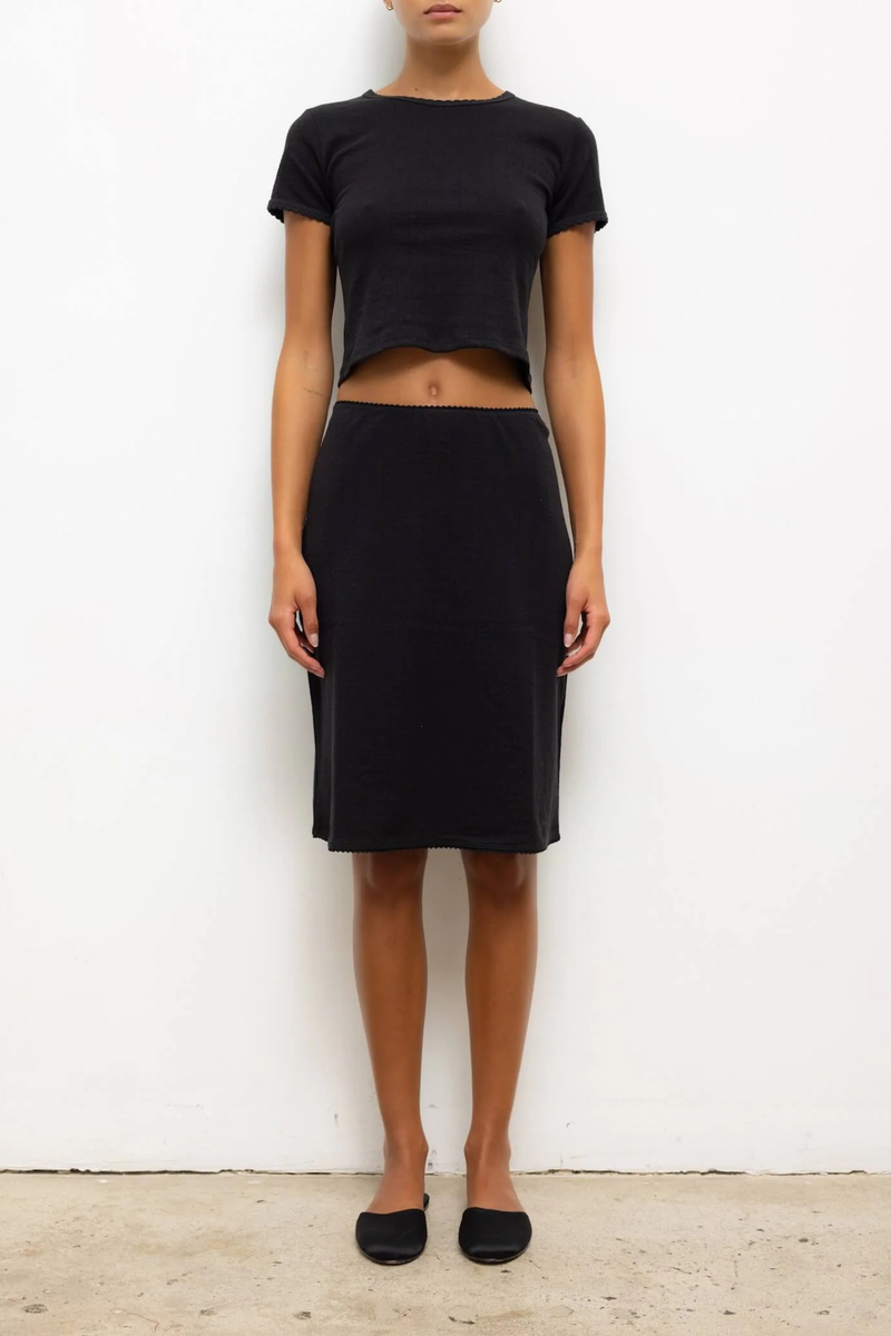 front profile model wearing  Pointelle Baby Tee Black slim fit tee
Cropped length
Cap-style sleeve
Classic crew neckline
Signature pinhole stripes
Delicate eyelets
Scalloped edging
100% Cotton