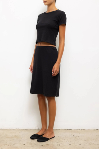 side profile model wearing  Pointelle Baby Tee Black slim fit tee
Cropped length
Cap-style sleeve
Classic crew neckline
Signature pinhole stripes
Delicate eyelets
Scalloped edging
100% Cotton