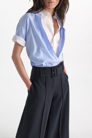 front profile model wearing Powerful Ease Blouse oxford blue white 100 % Cotton
Full double-layer cropped blouson blouse with half sleeves
First layer in white stretch poplin, top layer in light blue oxford
First layer has a hidden placket
Top layer with chest pocket and without buttons
Turn up cuffs
Elastic hem