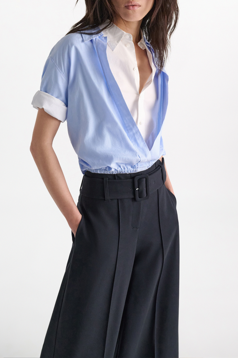 front profile model wearing Powerful Ease Blouse oxford blue white 100 % Cotton
Full double-layer cropped blouson blouse with half sleeves
First layer in white stretch poplin, top layer in light blue oxford
First layer has a hidden placket
Top layer with chest pocket and without buttons
Turn up cuffs
Elastic hem