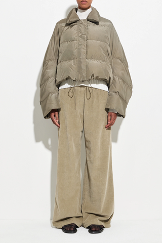 front profile model wearing Puffer Coat olive cropped fit Wide sleeves that taper gently at the cuff, elastic drawcord hem