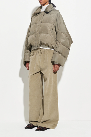 side profile model wearing Puffer Coat olive cropped fit Wide sleeves that taper gently at the cuff, elastic drawcord hem