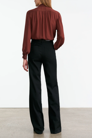 back profile model wearing Revi Silk Blouse burgundy Relaxed fit, Collar stand,
Front yoke and sleeves with shirring
Billowy sleeves with buttoned cuffs and slits