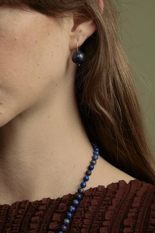 model wearing  Rosette Drop Earrings Blue Lapis Blue lapis bead is suspended against a single sterling silver hoop
Crafted in sterling silver, with blue round lapis
Blue lapis diameter 12mm