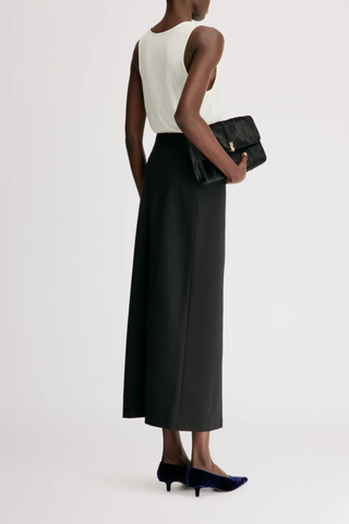 back profile model wearing  Samos Fitted Straight Maxi Skirt Virgin Wool/Elastane black Virgin wool grain de poudre
Maxi length pencil skirt
Side zipper fastening
Back vent
95% VIRGIN WOOL 5% ELASTANE