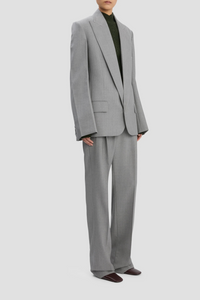 side profile model wearing Sculptural Sleeve Jacket light grey virgin wool oversized fit 3-hole button on cuff with contrast white stitch detail