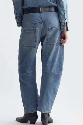 back profile model wearing Shon Jeans Cienna Wash mid blue wash Mid-rise
Relaxed fit
Barrel leg jean
Uniquely curved silhouette
Seam detail at knees
Gusset at inseam
Zip fly
Shank closure
Top-stitched front and back patch pockets
Belt loops
100% Cotton