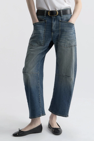 front profile model wearing Shon Jeans Classic Wash mid wash blue Mid-rise
Relaxed fit
Barrel leg jean
 curved silhouette
Seam detail at knees
Gusset at inseam
Top-stitched front and back patch pockets
Belt loops
100% Cotton