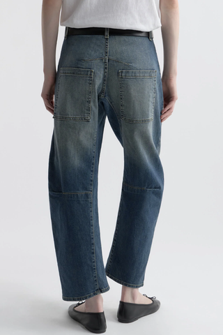 back profile model wearing Shon Jeans Classic Wash mid wash blue Mid-rise
Relaxed fit
Barrel leg jean
 curved silhouette
Seam detail at knees
Gusset at inseam
Top-stitched front and back patch pockets
Belt loops
100% Cotton