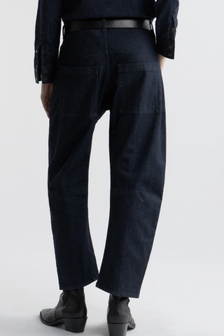 back profile model wearing Shon Jeans Indigo Rinse cotton Mid-rise
Relaxed fit
Barrel leg jean
Uniquely curved silhouette
Seam detail at knees
Gusset at inseam
Zip fly
Shank closure
Top-stitched front and back patch pockets
Belt loops