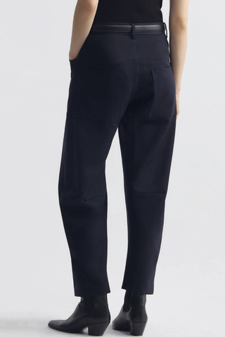back profile model wearing  Shon Wool Gaberdine Pant Midnight navy wool Mid-rise
Relaxed fit barrel leg pant
Uniquely curved silhouette
Seam detail at knees
Gusset at inseam
