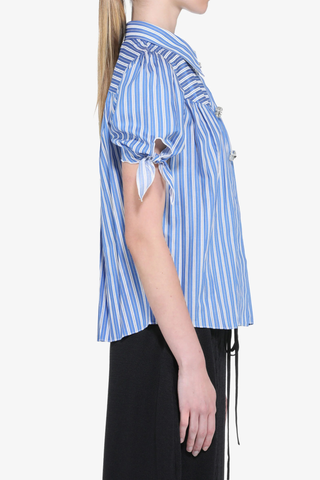 side profile model wearing Short Sleeve Striped Top blue white stripe cotton Short sleeve
Classic collar
Blue and white pattern runs throughout the garment
Front closure features large jewel buttons
Puffed sleeves close with a tied ribbon