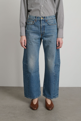 front profile model wearing Slim Lasso Jane Jean mid blue wash high rise relaxed fit cropped inseam barrel leg