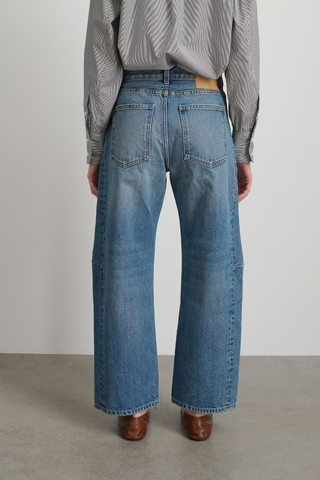 back profile model wearing Slim Lasso Jane Jean mid blue wash high rise relaxed fit cropped inseam barrel leg