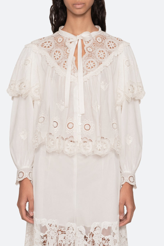 front profile model wearing Embroidered long sleeve
Long puff sleeves
Scalloped hem
Tie at the neckline
Self-100% cotton
Embroidery-100% polyester
Button front