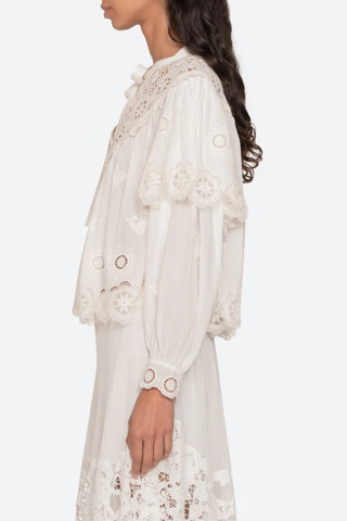side profile model wearing Embroidered long sleeve
Long puff sleeves
Scalloped hem
Tie at the neckline
Self-100% cotton
Embroidery-100% polyester
Button front