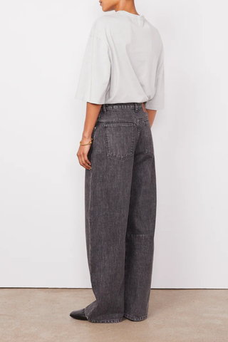 back profile model wearing Sora Denim Anthracite Low-waisted 5 pockets, loose fit
100% Cotton
Curved and wide leg
Darts at knees
Tone on tone topstitching
Silver jeans button and rivets.