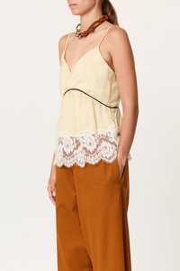 side profile model wearing  Striped Cami With Lace egg yellow Striped cupro top
V-neckline
Contrast empire waist piping
Deep scalloped lace hem