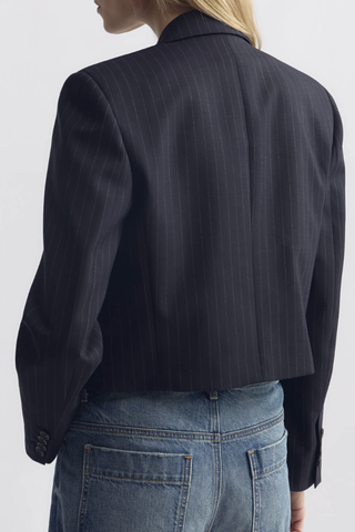 back profile model wearing Swan Jacket midnight blue wool Boxy, cropped silhouette
Structured shoulder pads
Single-breasted
Fully lined
Internal chest pocket
Buttons at cuffs
Undercollar felt detail at back