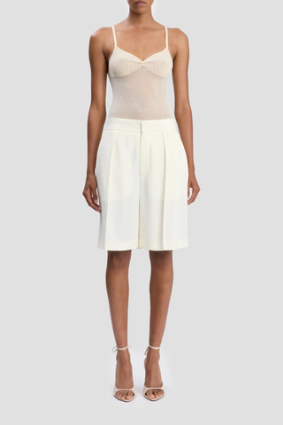 front profile model wearing Tailored Fluid Twill Short ivory Recycled fluid wool fabrication
Knee length
Elasticated back waistband
Zip fly with hook &amp; bar closure
Front pleats
Side pockets
Back jet pockets