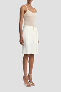 side profile model wearing Tailored Fluid Twill Short ivory Recycled fluid wool fabrication
Knee length
Elasticated back waistband
Zip fly with hook &amp; bar closure
Front pleats
Side pockets
Back jet pockets