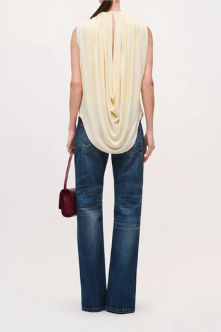 back profile model wearing  The Astor Draped Jersey Top Butter Cascading folds
Sleeveless
Deep cowl-neck draping
Fitted silhouette through the waist
100% Viscose Jersey