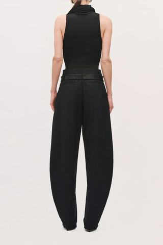 back profile model wearing  The Dean Cotton Pant black High-rise with front pleats
Voluminous tapered leg
Hits at the ankle
Belt loops
Self: 100% Cotton
Lining: 60% Acetate, 40% Polyester