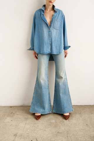 front profile model wearing The Essential Denim Shirt worn indigo mid wash blue relaxed shape
Button at the chest 
Button under the neckline 
Small button perfectly placed on the hidden cuff placket 
100% Cotton
Medium faded vintage inspired indigo 