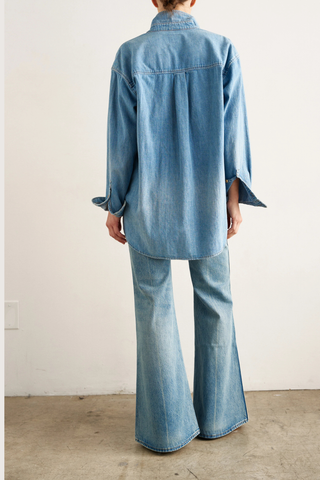 back profile model wearing The Essential Denim Shirt worn indigo mid wash blue relaxed shape
Button at the chest 
Button under the neckline 
Small button perfectly placed on the hidden cuff placket 
100% Cotton
Medium faded vintage inspired indigo 