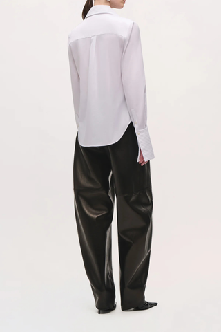 back profile model wearing The Inez Tuxedo Shirt With Tie Neck Scarf white cotton poplin Crisp shirting
Tuxedo-inspired silhouette
Pintucked front detailing
Integrated neck scarf
Pointed collar
Long sleeves
Elongated pintucked cuffs
Button-front closure
Curved shirttail hem