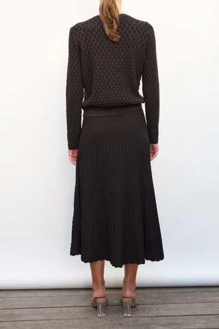back profile model wearing Thelma Skirt ebony deep black Two-tone
Pleated “arrow”-patterned knit
Mid-length cut
Wicker-style knit skirt
High waist
Wide scalloped waistband
50% viscose, 45% pure extra-soft virgin wool, 5% polyester