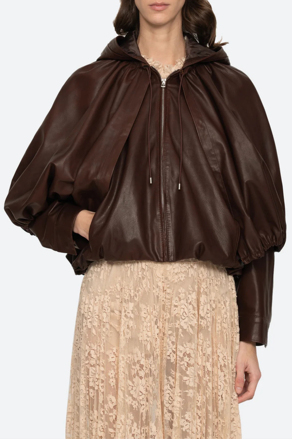 front profile model wearing Thompson Leather Cape Jacket brown 
bubble hem
Adjustable drawstrings
attached hood
Self-100% lamb leather | Lining-100% polyester
Front zipper
Oversized, relaxed fit
100% Lamb Leather