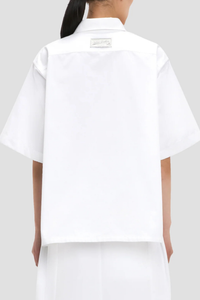 back profile model wearing Trapeze Short Sleeve Shirt optical white with logo patch on the backCollared neckline
High hip length
Shirt sleeves
Covered back
Chest pocket
Front buttons
100% Cotton with logo patch on the back