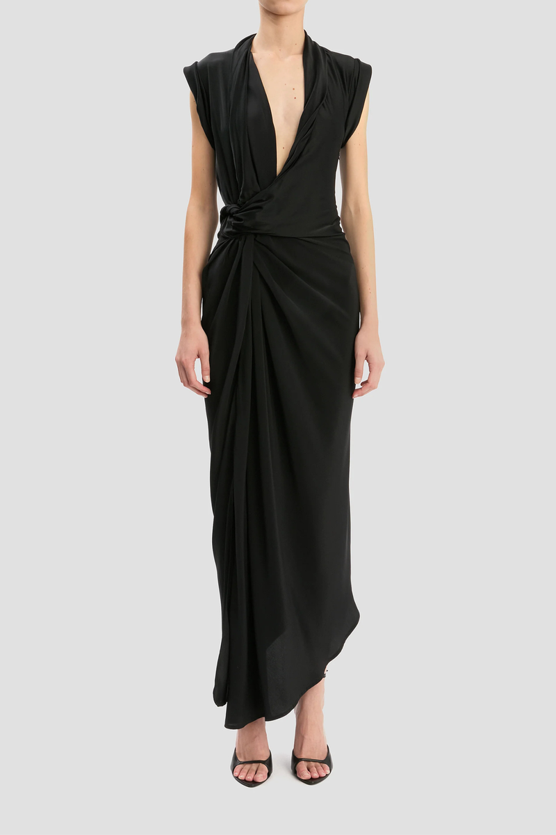 front profile model wearing Twist Detail CDC Dress Black Asymmetric, drape midi dress
High shine jersey bodice
Crepe de chine skirt
Wrap front neckline with button &amp; thread loop closure
Short roll sleeve
Twist drape waist detail
Front skirt split
Concealed side zip