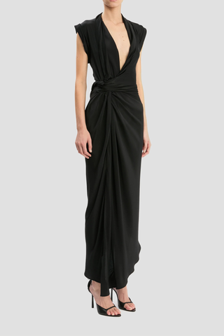 side profile model wearing Twist Detail CDC Dress Black Asymmetric, drape midi dress
High shine jersey bodice
Crepe de chine skirt
Wrap front neckline with button &amp; thread loop closure
Short roll sleeve
Twist drape waist detail
Front skirt split
Concealed side zip