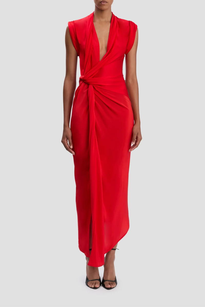 front profile model wearing Twist Detail CDC Dress Red Asymmetric, drape midi dress
High shine jersey bodice
Crepe de chine skirt
Wrap front neckline with button &amp; thread loop closure
Short roll sleeve
Twist drape waist detail
Front skirt split
Concealed side zip