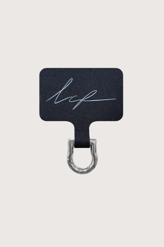 flat lay Universal Adapter Silver 
Fits discreetly into your existing case
A removable carabiner protrudes slightly from the charging connector, making it easy to attach your chain
Made of square black branded fabric with a stainless steel coating