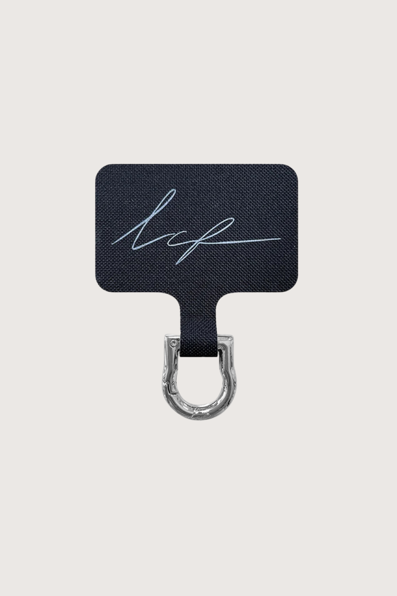 flat lay Universal Adapter Silver 
Fits discreetly into your existing case
A removable carabiner protrudes slightly from the charging connector, making it easy to attach your chain
Made of square black branded fabric with a stainless steel coating
